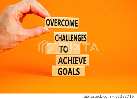 Overcome challenges to achieve goals symbol. Concept words Overcome challenges to achieve goals on wooden blocks on a beautiful orange background. Businessman hand. Business goals concept. Copy space. Overcome challenges to achieve goals symbol. Concept words Overcome challenges to achieve goals on wooden blocks on a beautiful orange background. Businessman hand. Business goals concept. Copy space. 95352719