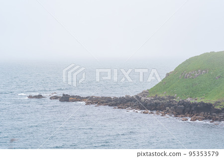 high deserted grassy shore over a cold foggy sea 95353579