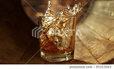 Ice cube falling into glass of whisky in wooden barrel. Ice cube falling into glass of whisky in wooden barrel. 95353883
