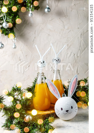 Orange drink decorated with white rabbit on light background for children party. Orange drink decorated with white rabbit on light background for children party. 95354185