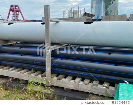 Large plastic pipes of large diameter with flanges in an open-air storage warehouse for the storage of materials and industrial equipment Large plastic pipes of large diameter with flanges in an open-air storage warehouse for the storage of materials and industrial equipment 95354475