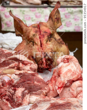 Raw pork with pig head on table in butchery Raw pork with pig head on table in butchery 95354917