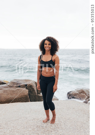 Full length of slim woman with a mat by the ocean Full length of slim woman with a mat by the ocean 95355013