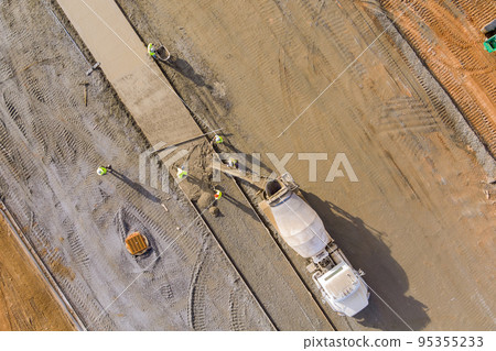 Concrete mix truck an workers poured concrete onto for to sidewalk on construction site 95355233