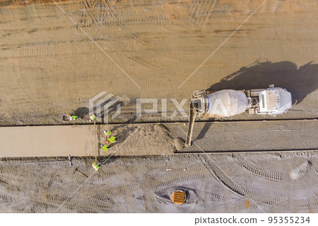 An concrete mix truck pouring concrete at construction site during workers pouring of cement for sidewalk An concrete mix truck pouring concrete at construction site during workers pouring of cement for sidewalk 95355234