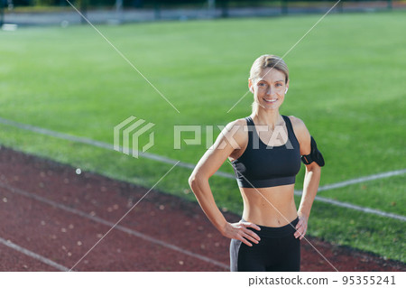 Portrait of sportswoman in sportswear at stadium, blonde smiling and looking at camera, woman before morning workout and exercise and fitness. Portrait of sportswoman in sportswear at stadium, blonde smiling and looking at camera, woman before morning workout and exercise and fitness. 95355241