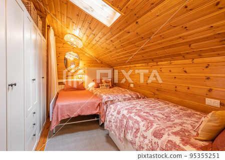 Cozy bedroom with three beds and white wardrobe in a modern cottage with wooden walls Cozy bedroom with three beds and white wardrobe in a modern cottage with wooden walls 95355251