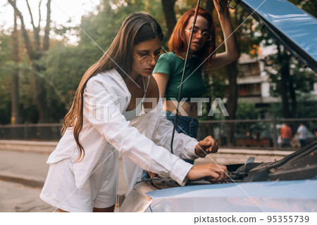 Two women with broken car on the road. Open hood Two women with broken car on the road. Open hood 95355739
