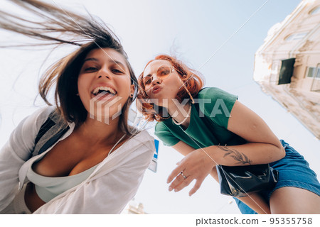 Two friends looks down outdoors in the street at camera Two friends looks down outdoors in the street at camera 95355758