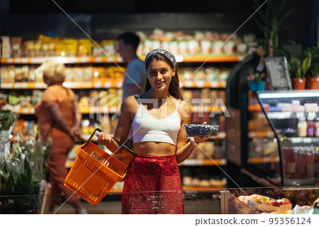 young woman do shopping in supermarket. choosing blueberry in store 95356124