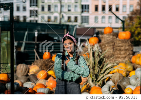 Farmer woman sells autumn pumpkin harvest at the market Farmer woman sells autumn pumpkin harvest at the market 95356313