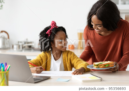 Snack Time. Loving Black Mother Bringing Sandwiches To Daughter Study With Laptop 95356693