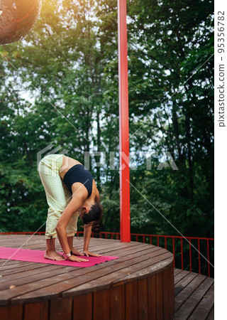 A young woman in doing yoga in the yard 95356782