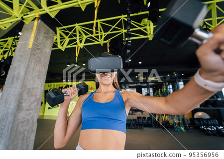 Woman wearing glasses of the virtual reality exercising with dumbbells 95356956