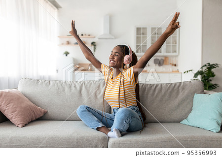 Positive young black woman with wireless headset dancing 95356993