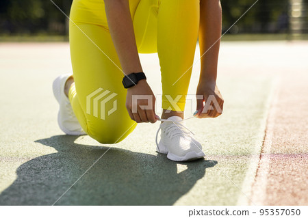 Black Woman In Yellow Sportswear Tying Shoelace On Stadium 95357050
