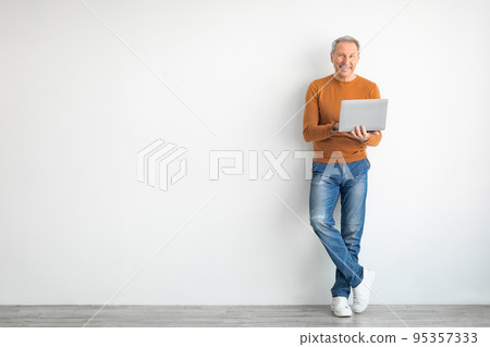 Confident mature man using laptop at home 95357333