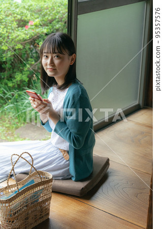 A young woman looking at a smartphone on the porch 95357576