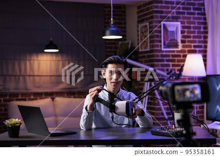 Male vlogger livestreaming product review on internet channel, filming vr glasses recommendation with podcast equipment at sound station. Recording online video with virtual reality goggles. 95358161