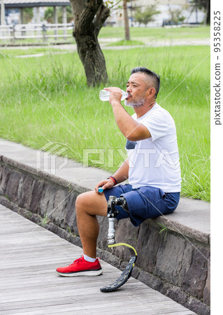 Disabled man with a prosthetic leg taking a break Disabled man with a prosthetic leg taking a break 95358225