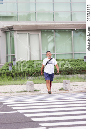 Disabled man with a prosthetic leg crossing the pedestrian crossing 95358353