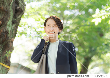 A woman in a suit walking on a green road 95359325