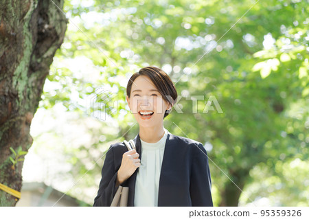 A woman in a suit walking on a green road A woman in a suit walking on a green road 95359326