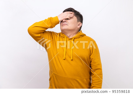 Don't want to look at this. Portrait of middle aged man covers eyes, disgust from something shameful, scared afraid to see, wearing urban style hoodie. Indoor studio shot isolated on white background. 95359818