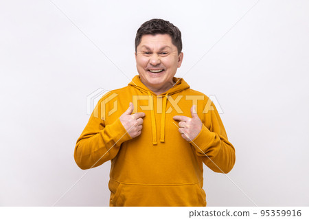 Proud satisfied man pointing fingers on himself and looking at camera with toothy smile, extremely satisfied, wearing urban style hoodie. Indoor studio shot isolated on white background. 95359916