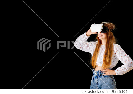 Young woman in white shirt and jeans wearing virtual helmet. Woman standing with folded hands. Young woman in white shirt and jeans wearing virtual helmet. Woman standing with folded hands. 95363041