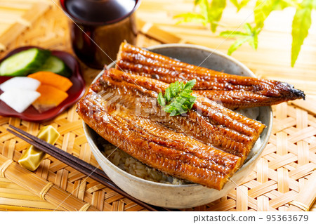 Eel bowl and green leaves on a bamboo mat 95363679