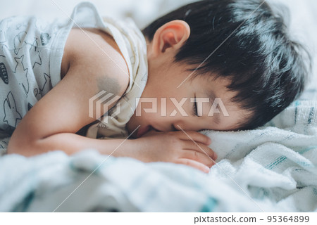 A 2-year-old boy taking a nap while sucking his thumb 95364899