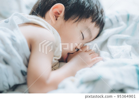 A 2-year-old boy taking a nap while sucking his thumb A 2-year-old boy taking a nap while sucking his thumb 95364901