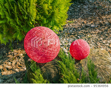 Balls of thread on a green flowerbed of a public park. Balls of thread on a green flowerbed of a public park. 95364956