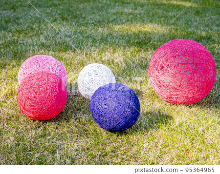 Colored balls of wound thread on a grassy lawn. Colored balls of wound thread on a grassy lawn. 95364965