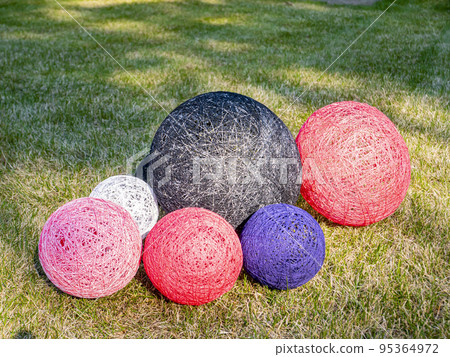 Colored balls of wound thread on a grassy lawn. Colored balls of wound thread on a grassy lawn. 95364972