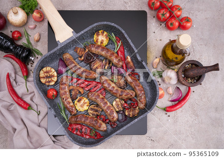 Grilled sausages and vegetables on a grill frying pan on a domestic kitchen 95365109
