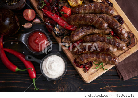 Grilled sausages and vegetables on wooden cutting board at domestic kitchen Grilled sausages and vegetables on wooden cutting board at domestic kitchen 95365115