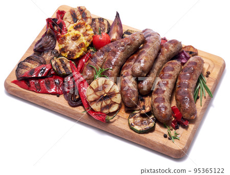 Grilled sausages and vegetables on wooden cutting board isolated on white background Grilled sausages and vegetables on wooden cutting board isolated on white background 95365122