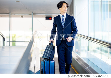 Businessman walking through airport aisle 95365655