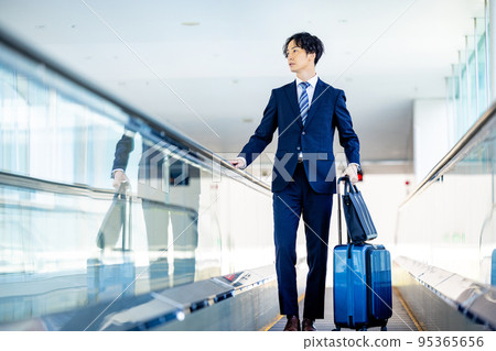Businessman walking through airport aisle 95365656