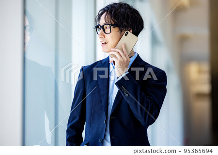Smiling young man with smartphone in office corridor 95365694