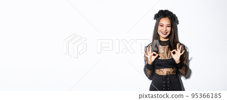 Cheerful beautiful asian woman in witch dress showing okay gestures and smiling satisfied, approve halloween costume or advertisement, standing over white background Cheerful beautiful asian woman in witch dress showing okay gestures and smiling satisfied, approve halloween costume or advertisement, standing over white background 95366185
