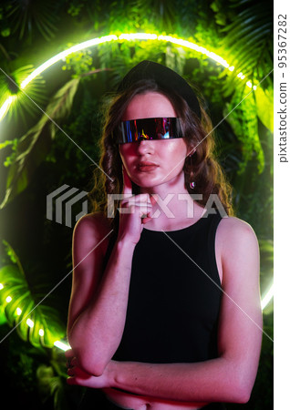 Caucasian woman in panoramic sunglasses against the background of an annular neon lamp in plants.  95367282