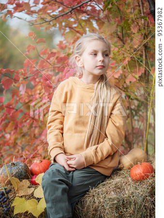 Girl in the hay with pumpkins 95367982