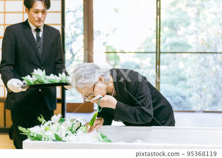 An elderly woman (crying) who performs a flower vase ceremony at a funeral coffin ceremony An elderly woman (crying) who performs a flower vase ceremony at a funeral coffin ceremony 95368119