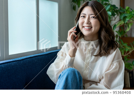 Young woman calling on the sofa Young woman calling on the sofa 95368408