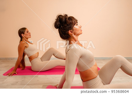 Young womans with long hair, fitness instructor in beige sportswear, preparing for stretching and pilates on yoga mat in the gym. Female fitness yoga concept. Healthy lifestyle harmony and meditation. 95368604