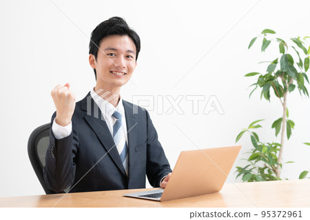 使用個人電腦工作的年輕商人（膽量姿勢、成功、成就） 95372961