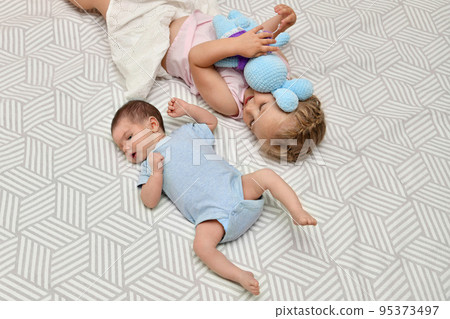 Big sister looks with adoration at little brother 95373497